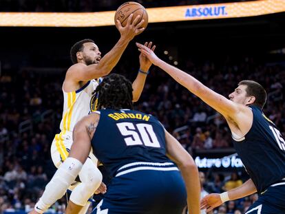 Stephen Curry, de los Golden State Warriors, trata de encestar frente a Nikola Jokic, de los Denver Nuggets, la semana pasada en un partido de pretemporada.