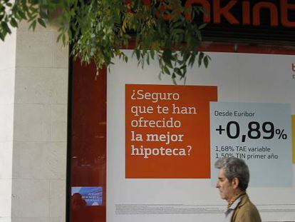 Un hombre pasando por delante de una oficina de Bankinter con una oferta hipotecaria