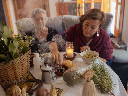 Pepa Amaya (a la izquierda) quema incienso junto a algunas de las hierbas con las que elabora un alcohol que regala como remedio natural. Junto a ella, su amiga María Jesús Fernández.