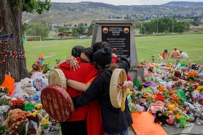 Personas de la Nación Cree se abrazan frente a un memorial en honor a los menores fallecidos en Kamloops.