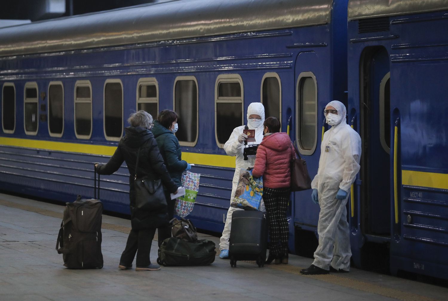 Trabajadores con trajes de protección chequean los documentos de los pasajeros en la estación de Kiev a punto de subir a un tren hacia Moscú.