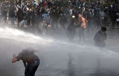Estudiantes chilenos que participaban en las protestas del pasado día 1 en Santiago reciben un chorro de agua lanzado por la policía.