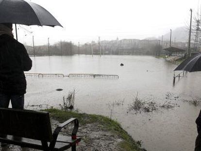 Vecinos de Hernani, observan el campo de rugby Landare, anegado por el desbordamiento del r&iacute;o Urumea.
