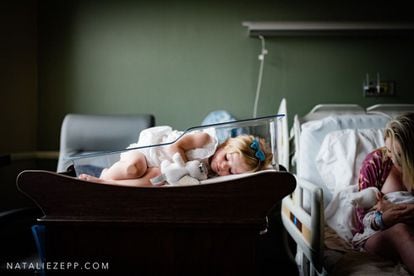 'Denial' (Negación), de Estados Unidos. Esta foto ha sido una de las elegidas en la categoría de posparto. Mientras la madre da de comer al recién nacido, su hermana duerme en la cama nido.