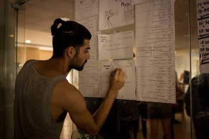 Rabi, un voluntario y huésped sirio, apunta una de las actividades para el jueves en la puerta del comedor principal del hotel.