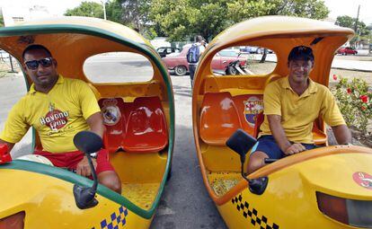 Dos taxistas en La Habana con escudos de Barça y Madrid.