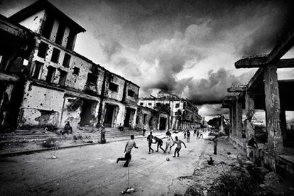 Un grupo de niños juega al fútbol en una calle de Mogadiscio entre edificios en ruinas por los enfrentamientos armados. Esta fotografía forma parte de <i>Somalia en el fin del mundo</i>, reportaje fotográfico galardonado con el Premio Ortega y Gasset de Fotografía 2009, publicado en el <i>Magazine</i> de <i>La Vanguardia</i> del 1 de febrero de 2009.