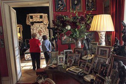 Fotos sobre el piano de Duarte Pinto; al fondo dos mujeres contemplan el dormitorio del decorador.