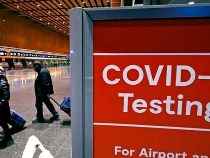 Dos viajeros pasan ante una señal de tests de covid, el pasado 21 de diciembre en el aeropuerto Logan, en Boston.