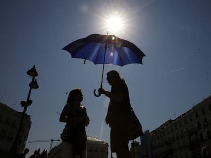 Turistes es protegeixen de la calor a la Puerta del Sol de Madrid.