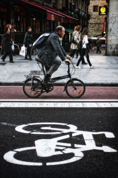 Un hombre circula con bicicleta plegable por un carril bici en el centro de Madrid.