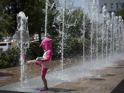 Una nena es refresca en una font, a Barcelona.