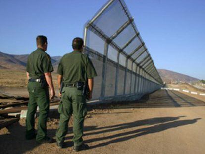 Dos policías vigilan la frontera de México con EE UU.