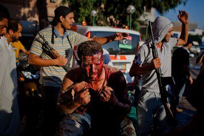 Varios rebeldes protegen a un leal a Gadafi de ser linchado a las puertas del hospital Central de Trípoli.