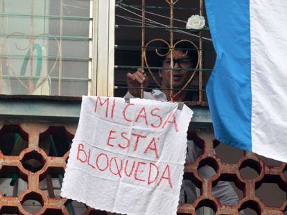 Cuban dissident and leader of Archipielago movement Yunior Garcia looks out his apartment's window showing a sign reading �My house is blocked�, in Havana, on November 14, 2021. - Garcia, leader of the demonstration called for November 15, denounced on Friday November 12 that Cuban State Security agents warned him that they will arrest him if he tries to march alone on Sunday, as planned. (Photo by AFP)