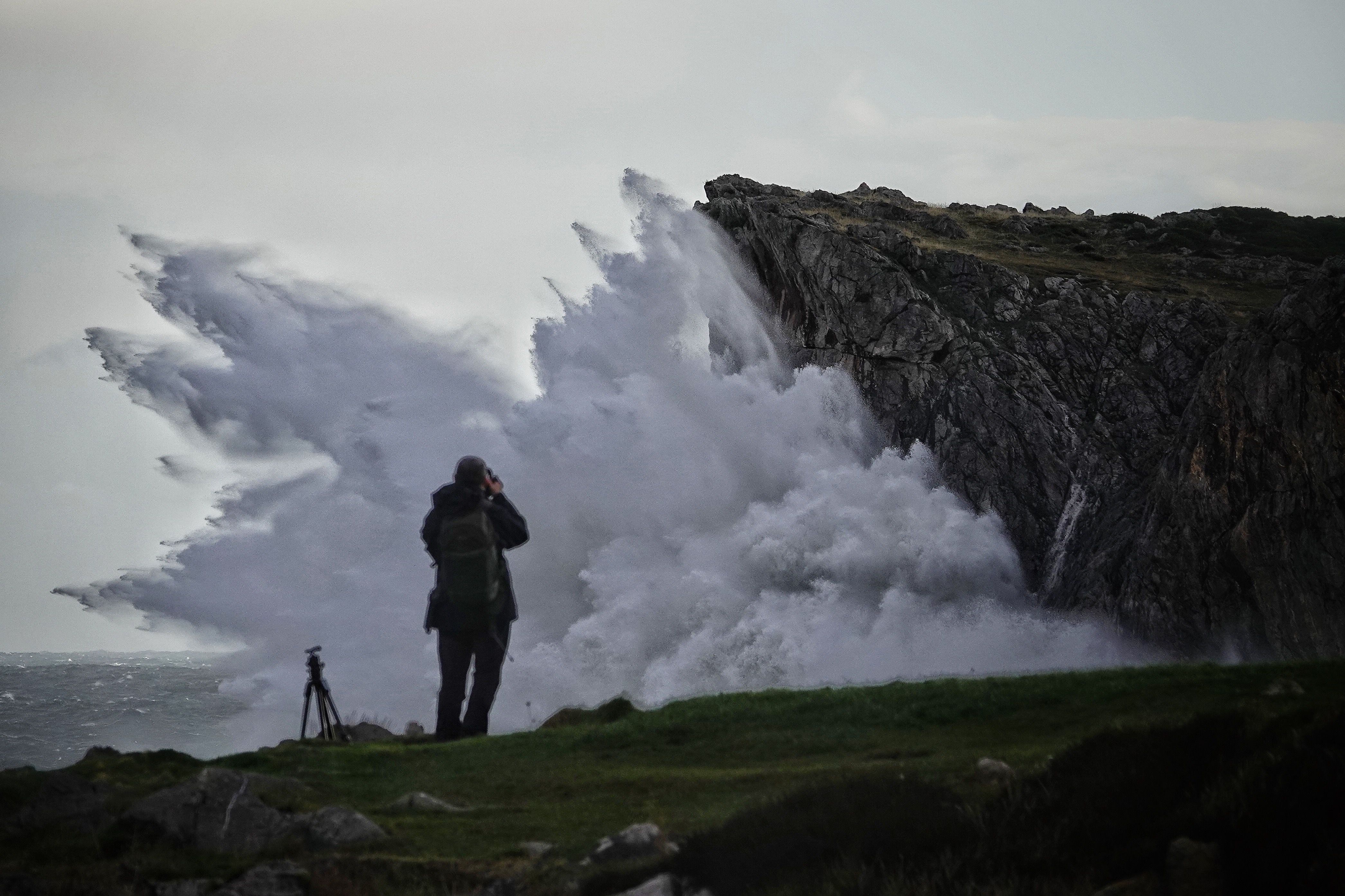 Una persona tomaba fotografías del oleaje en los bufones de Pría, este jueves en Llanes (Asturias). 