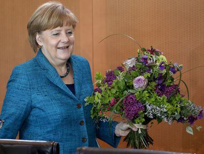 Angela Merkel con una ramo de flores para el secretario de Presidencia, por su cumpleaños.