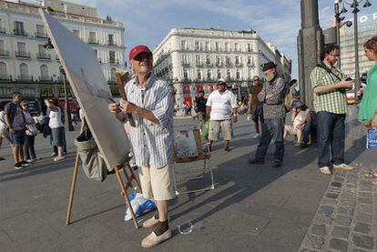 El pintor manchego Antonio López, en la Puerta del Sol trabajando en un lienzo sobre la Casa de Correos.