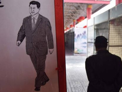 Un hombre camina junto a una imagen del presidente chino, Xi Jinping, este lunes en un mercado de Pequ&iacute;n.
 