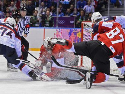 Los jugadores de EEUU y Canadá pelean por el disco.