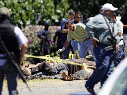 Trabajadores forenses realizan el levantamiento de los 17 cad&aacute;veres este domingo.