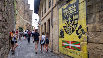 Un grupo de jóvenes pasa delante de un mural a favor de la independencia en una calle de Pasajes de San Juan (Gipuzkoa).