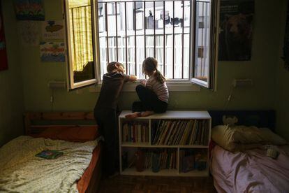 Dos hermanos miran por la ventana de su dormitorio durante el confinamiento en Madrid, el 13 de abril. Ansiedad, obesidad y somatizaciones del estrés son los problemas frecuentes. Sanidad encargó a la Asociación Nacional de Pediatría un informe para estudiar las condiciones de salida de los menores a la calle.