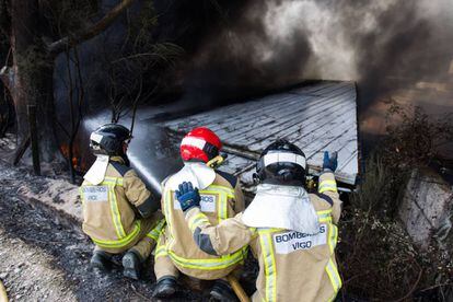 Un grup de bombers treballa apagant les flames d'una nau al polígon industrial de Puxeiros, a Mos (Pontevedra).