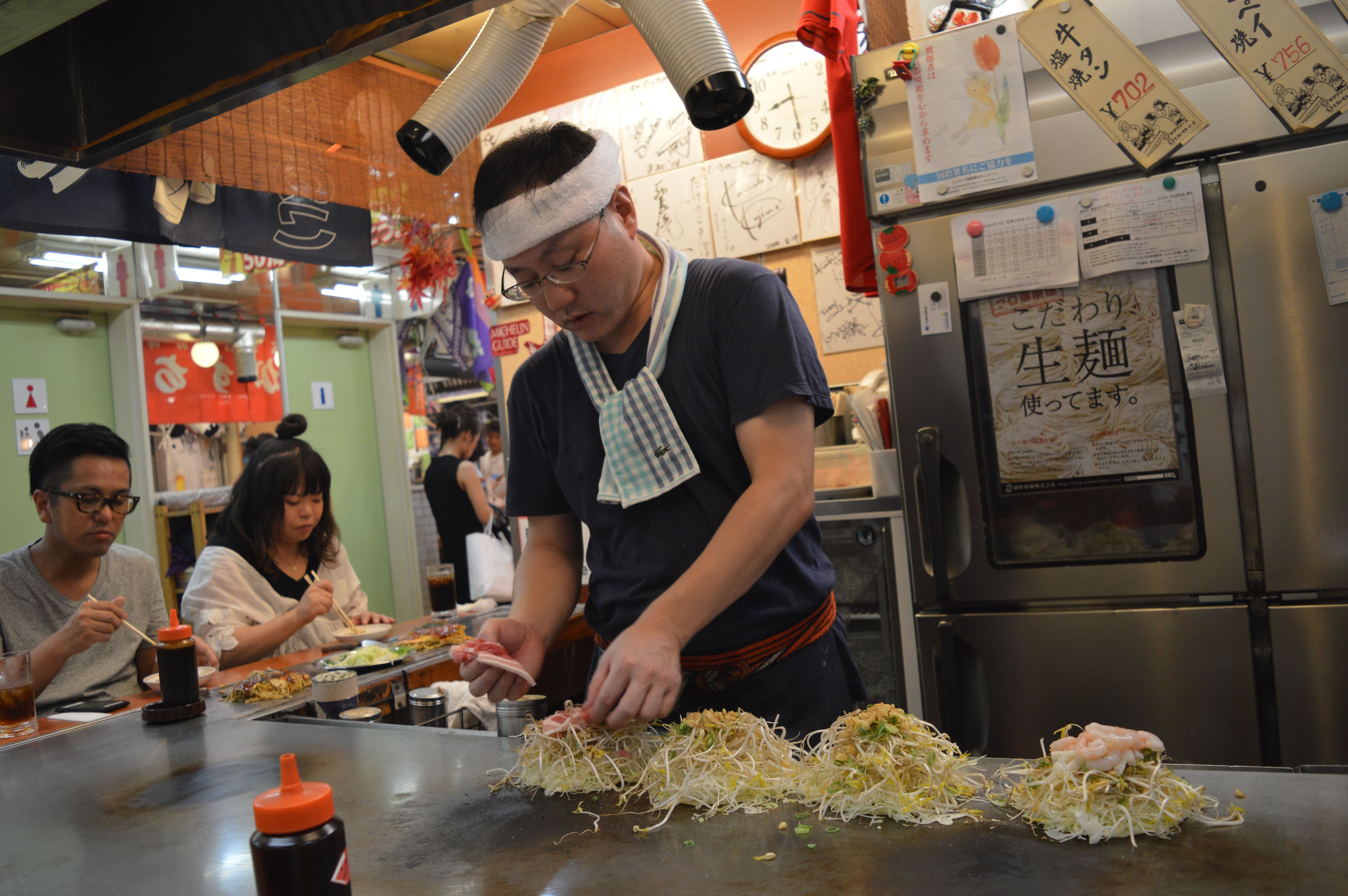 El cocinero va colocando los ingredientes del okonomiyaki en un restaurante de Hiroshima.