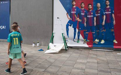 Un chico con la camiseta de Neymar pasa frente al nuevo póster sin el brasileño.