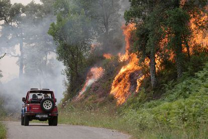 Un coche pasaba el viernes cerca de las llamas del incendio forestal de Samos (Lugo). En Galicia, una región por lo general fresca en el noroeste del país, pero que ha registrado muy altas temperaturas esta semana, varios fuegos han quemado más de 3.500 hectáreas.
