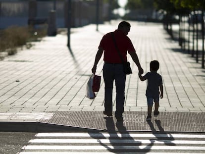 Un hombre lleva a su hijo al colegio, en una fotografía de archivo.