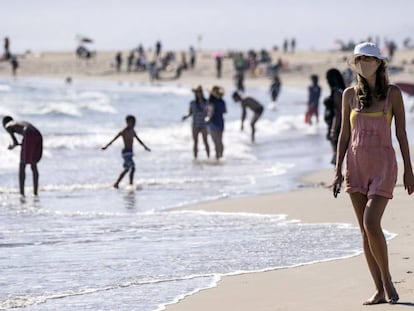 Una turista con mascarrilla pasea por una playa en Los Angeles (California)