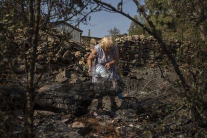 Una mujer echaba agua el martes en una zona de vegetación afectada por el incendio de Losacio, en Zamora, que ha obligado a desalojar 17 pueblos. 
