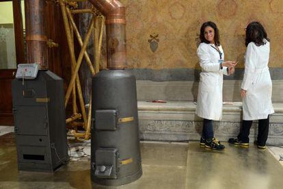 Trabajadoras ultimando los preparativos para el próximo cónclave en el Vaticano, junto a las estufas que se utilizarán durante la elección del Papa.
