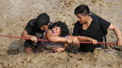 Una mujer es ayudada a salir de una riada en Huachipa, Per&uacute;, el pasado marzo. 