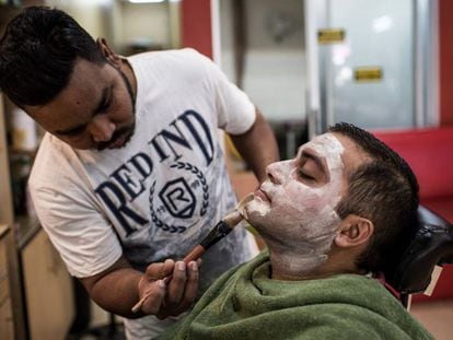 Aasif Khalifa aplica una máscara blanqueadora a su cliente Himesh Dhulab en su salón de belleza de Johannesburg (Sudáfrica), el 3 de agosto de 2018.