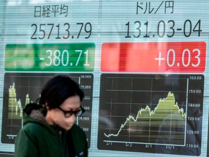 Una mujer pasa junto a un tablero electrónico que muestra la cotización del yen japonés frente al dólar en Tokio.