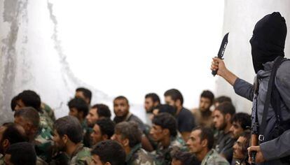 Un soldado del ISIS encapuchado vigila a un grupo de soldados sirios capturados en Raqqa en agosto de 2014.