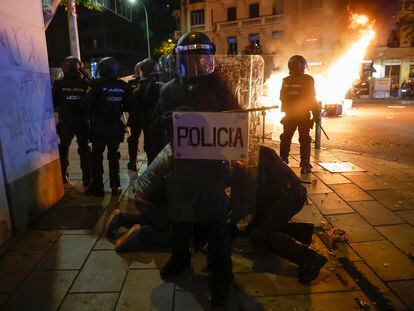 La policía detenía a una persona en Madrid al final de la protesta del jueves, mientras al fondo ardía el mobiliario urbano.