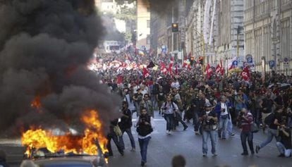 Varios vehículos arden hoy en el centro de Roma, durante la marcha de los indignados