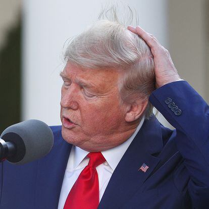 U.S. President Donald Trump holds onto his hair in a gust of wind as he addresses the daily coronavirus response briefing in the Rose Garden at the White House in Washington, U.S., March 30, 2020. REUTERS/Tom Brenner