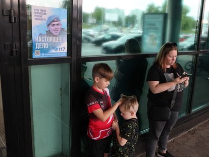 Una mujer y dos niños ante un cartel que llama a filas para defender a Rusia, en la entrada de un centro comercial de Smolensk, el pasado 22 de agosto.