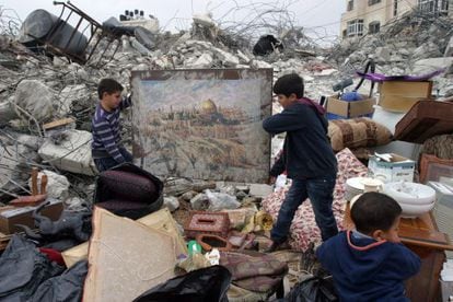 Niños palestinos sacan un cuadro que muestra la cúpula de la roca y las murallas de la Ciudad Vieja de entre los escombros de su casa, en Jerusalén este.