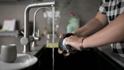 Una mujer friega un vaso en un piso de Barcelona.