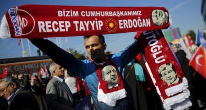 Un hombre sujeta banderas con la imagen y los nombres del presidente turco, Recep Tayyip Erdogan, y el primer ministro, Ahmet Davutoglu, mientras espera la llegada de este último al aeropuerto de Estambul, este martes.