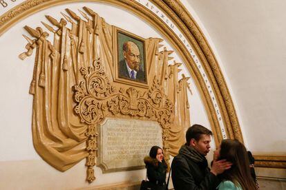 Una pareja se besa frente a un mosaico que representa a Vladimir Lenin en la estación de Kíyevskaya. Mosaicos, estatuas de mármol y vidrieras cuentan la historia del estado comunista en el metro.