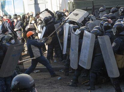 Al menos un manifestante ha resultado herido grave en los enfrentamientos registrados con la Policía cuando miles de manifestantes antigubernamentales han intentado llegar hasta la sede del Parlamento en Kiev, donde los parlamentarios están estudiando las demandas de la oposición de aprobar una nueva Constitución y un cambio de Gobierno, ha informado el diario 'Kiev Post'. En la imagen, un manifestante golpea a los policías en los alrededores del Parlamento de Kiev, 18 de febrero de 2014.