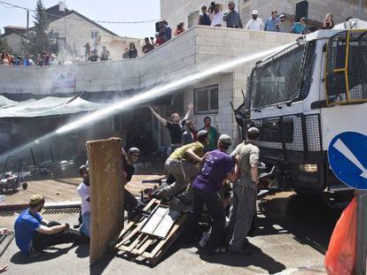 Agentes israel&iacute;es lanzan agua contra colonos del asentamiento de Beit EI, el mi&eacute;rcoles.