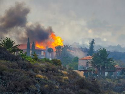 Una casa arde por los efectos de la erupción el volcán de La Palma este lunes mientras se observan en el cielo las nubes de cenizas y gases generadas.